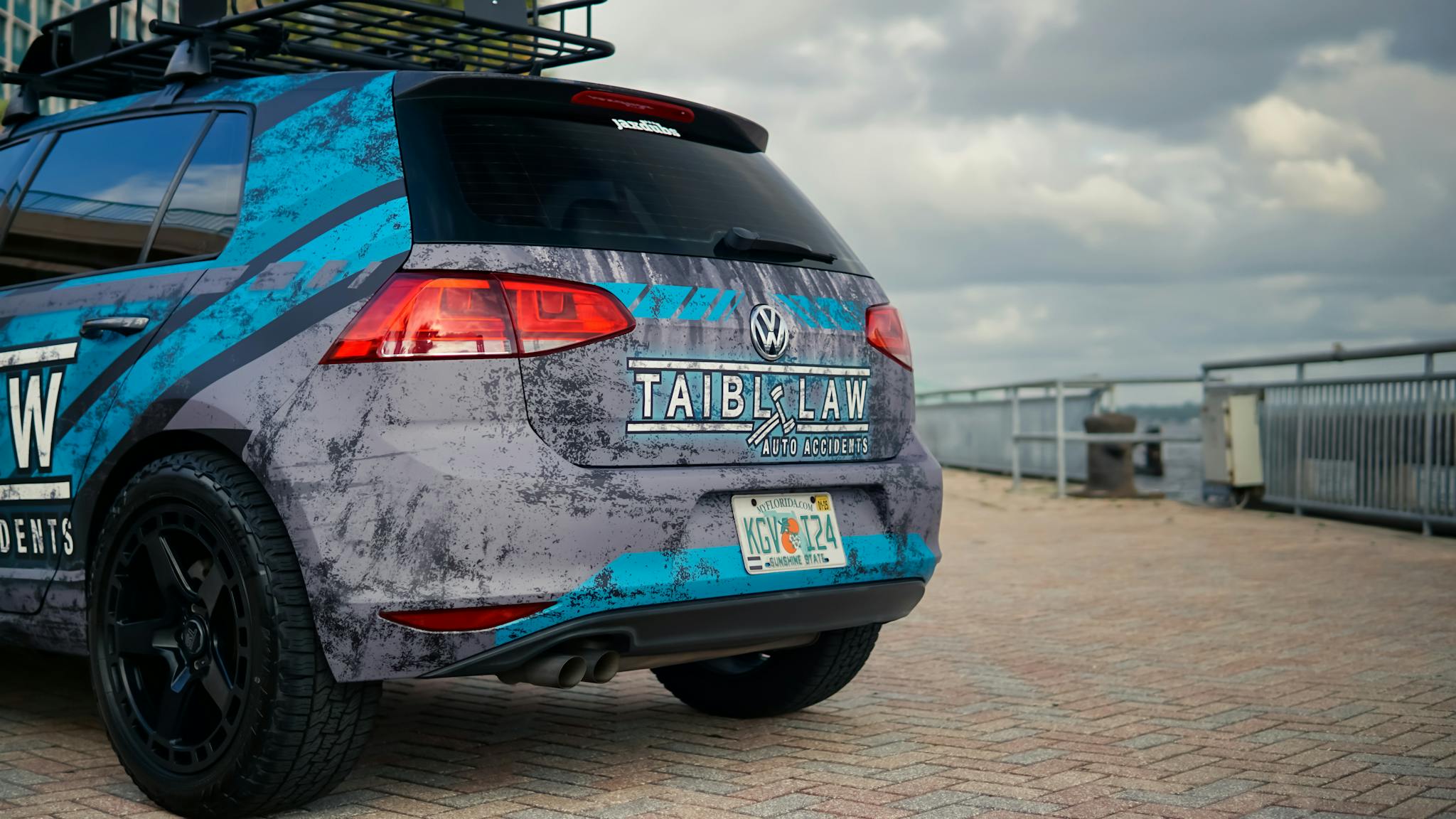 A custom-wrapped Volkswagen Golf parked outdoors showcasing vibrant branding.